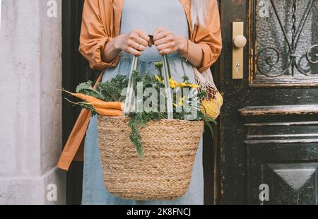 Frau, die einen Korbbeutel an der Tür hält Stockfoto