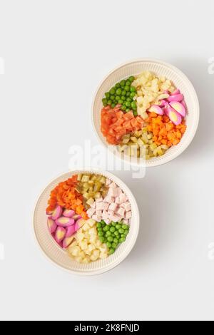 Set von Schüsseln mit frischen Zutaten für Olivier Salat vor weißem Hintergrund Stockfoto
