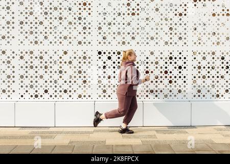 Übergewichtige junge Frau beim Joggen an der Wand Stockfoto