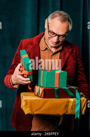 Lächelnder Mann, der mit einem offenen Geschenkkarton vor dem Vorhang steht Stockfoto
