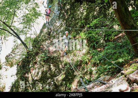 Junge, der auf Seilen mit Frau im Hintergrund läuft Stockfoto