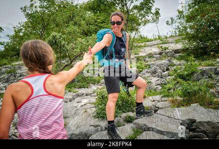 Glückliche Frau, die die Hand ihrer Tochter beim Bergsteigen hält Stockfoto