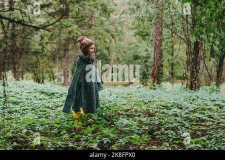 Mädchen trägt übergroßen Pullover stehen inmitten von Pflanzen im Wald Stockfoto