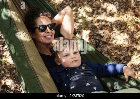 Lächelnde Frau mit Sohn, der sich in der Hängematte entspannt Stockfoto