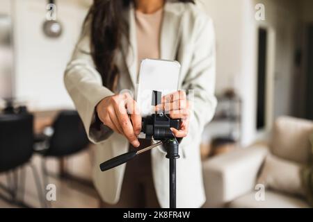 Frau, die das Smartphone zu Hause auf einem Stativ justiert Stockfoto