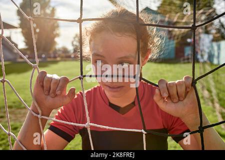 Mädchen durch das Netz auf dem Sportplatz an sonnigen Tag gesehen Stockfoto