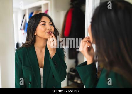 Junge Frau Anwendung Lippenstift zu Hause Stockfoto