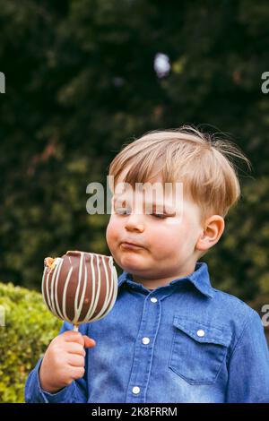 Niedlicher Junge mit Tafellapfel im Park Stockfoto