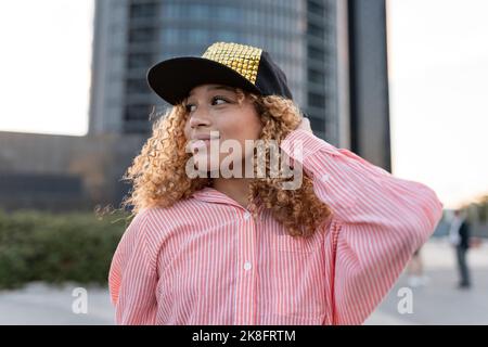 Lächelnde Frau im gestreiften Button-Down-Hemd mit Mütze Stockfoto