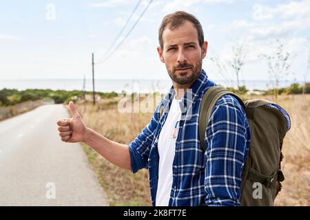 Mann im Rucksack, der die Daumen nach oben zeigte Stockfoto