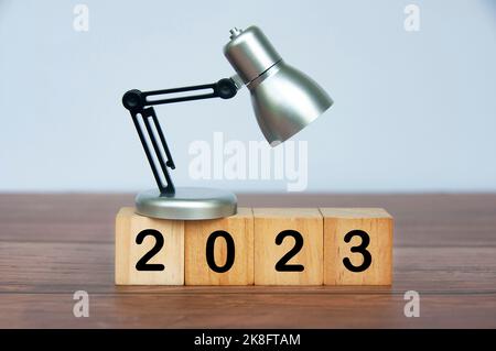 Tischlampe auf Holzwürfeln mit Jahr 2023. Konzept für das neue Jahr. Stockfoto