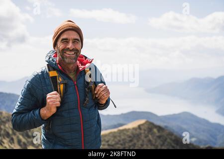 Glücklicher reifer Mann mit Strickmütze, der an einem sonnigen Tag steht Stockfoto