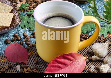 Tasse warmer Kaffee auf dem mit Herbstblättern verzierten Tisch Stockfoto