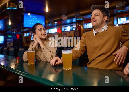 Fröhliche Freunde, die im Pub Bier trinken, genießen nette Gespräche Stockfoto