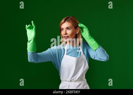 Frau in Handschuhen und Reinigungsschürze berühren virtuellen Bildschirm Stockfoto