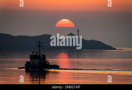 Sonnenaufgang, mit einem Boot im Vordergrund, über dem Leuchtturm der Trial Islands in der Juan de Fuca Strait in der Nähe von Victoria, British Columbia, Kanada. Stockfoto