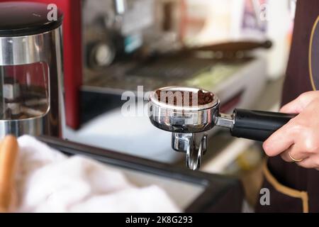 Eine Arbeiterin presst die fein gemahlenen Kaffeebohnen gegen einen Sabotagekontakt Stockfoto