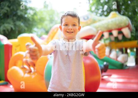 Fröhlicher Junge, der viel Spaß auf einem farbenfrohen, aufgeblassten Schloss hat Stockfoto