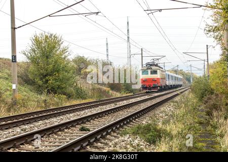 Ein elektrischer Personenzug fährt in einem nebligen Herbstmorgen. Eine Eisenbahnlinie in der Tschechischen Republik in der Nähe des Dorfes Hradcany. Zugpassagierentransponder Stockfoto