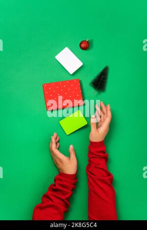 Minimale flache Lay von Bonuskartenvorlagen, Geschenkbox und weihnachtsobjekten in weiblichen Händen Konzept der Vorbereitung und Kauf von Geschenken für Weihnachten und New Y Stockfoto