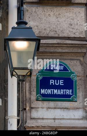 Traditionelles Pariser Straßenschild mit der Aufschrift „Rue Montmartre“ neben einer alten Straßenlampe im zweiten Arrondissement von Paris, Frankreich Stockfoto