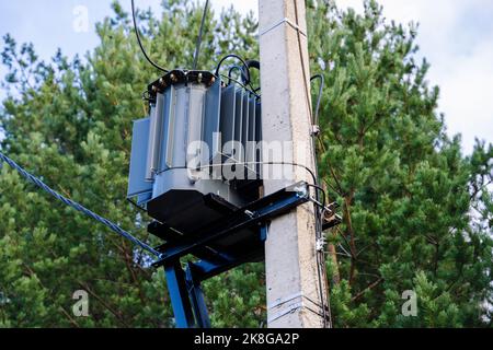 Netztransformator auf einem Stahlbetonmast installiert und befestigt Stockfoto