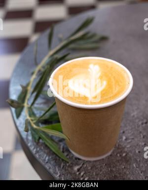 Frisch servierte Tasse Cappuccino mit Latte Art auf einem Holztisch in einem Café. Stockfoto