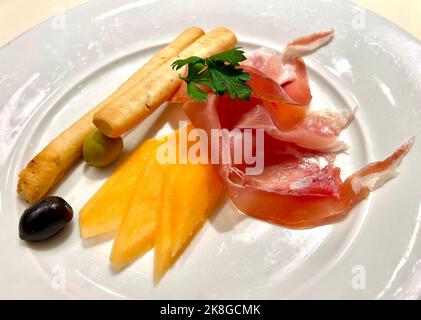 Ein serviertes Gericht aus Jamon Serrano mit Scheiben Wassermelone, Oliven und Brotscheiben Stockfoto