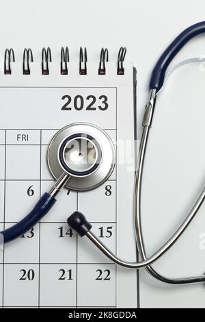 Seite mit Kalenderdaten für 2023 und Stethoskop als Medizinkonzept. Stockfoto