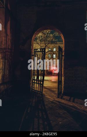 Altes Tor mit Gitter in der Nachtstadt Stockfoto