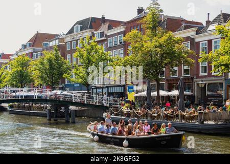 Blick auf das schöne Zentrum der Studentenstadt Leiden mit Terrassen und Vergnügungsbooten in den Kanälen. Stockfoto