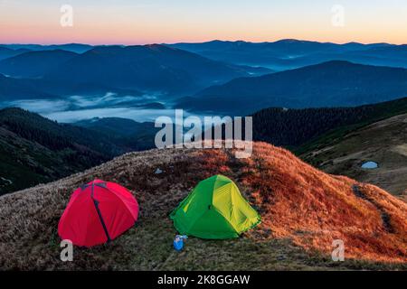 Am Morgen gibt es bunte Zelte auf dem Berggipfel. Wandern in den Bergen. Extremes Outdoor-Abenteuer Stockfoto