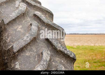 Nahaufnahme des Traktorreifens auf dem Bauernhof. Konzept zur Wartung von Laufflächenverschleiß, landwirtschaftlichen und landwirtschaftlichen Geräten. Stockfoto