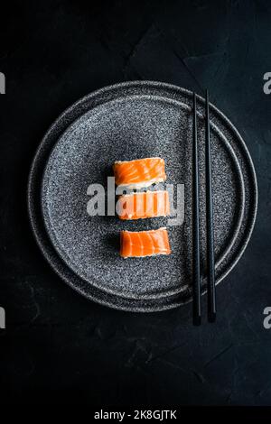 Von oben schwarzer Steinteller mit asiatischen Brötchen und Essstäbchen Stockfoto