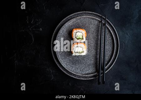 Von oben schwarzer Steinteller mit asiatischen Brötchen und Essstäbchen Stockfoto