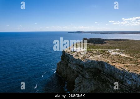 Von oben herrliche Fernsicht auf den Leuchtturm von Cape Cavalleria, der sich an sonnigen Tagen auf Menorca, Spanien, auf grünen Felsklippen vor dem ruhigen Meer befindet Stockfoto