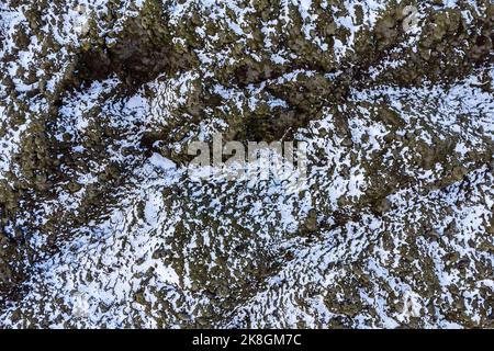 Luftaufnahme von oben auf raue Steinformationen mit weißem Schnee bedeckt an kalten Wintertagen im Hochland von Island Stockfoto