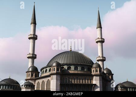 Niedriger Winkel der berühmten Taksim-Moschee mit Kuppeln und Minaretten, die sich vor blauem Himmel mit rosa Wolken auf der Straße von Istanbul, Türkei, befinden Stockfoto