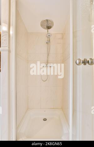 Duschhähne, die an der gefliesten Wand in der Nähe der Glaswand und der Zierschwanzwand im Waschraum zu Hause angebracht sind Stockfoto