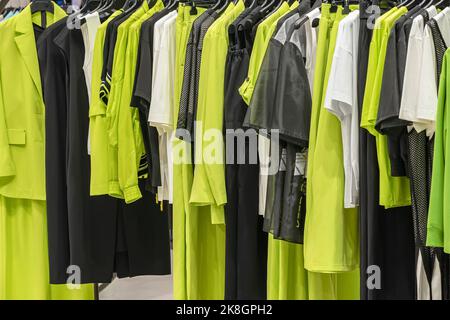 Sammlung weiblicher Kleidung an Kleiderbügeln in der Nähe des Ladens. Modenschau-Raum. Kaufhintergrund Stockfoto