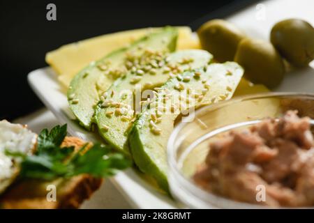 Appetitliche Avocado-Scheiben mit Sesam auf Käse. Frühstück am Morgen. Nahaufnahme. Stockfoto