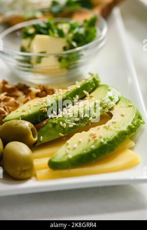 Appetitliche Avocado-Scheiben mit Sesam auf Käse. Frühstück am Morgen. Nahaufnahme. Stockfoto