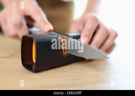 Frau schärft Messer mit speziellem Messerschärfer Stockfoto