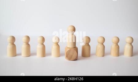 Die gewählte Person unter anderem. Eine menschliche Figur der grünen Farbe hebt sich von der Masse ab. Holzfiguren von Menschen. Ein talentierter Mitarbeiter, eine erfolgreiche Cho Stockfoto