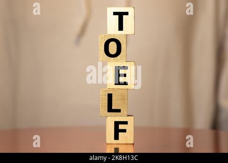 TOEFL - Wörter aus Holzblöcken mit Buchstaben, der Test des Englischen als Fremdsprache, TOEFL-Konzept, weißer Hintergrund. Stockfoto