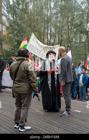 Demonstration gegen die iranische Regierung. Zeigt einen Mann mit Blut an den Händen, der eine Maske trägt, die dem iranischen Präsidenten ähnelt Stockfoto