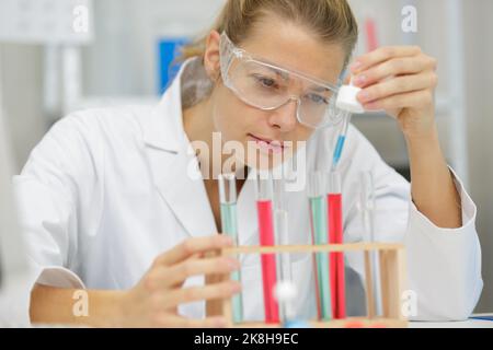 Frau, die im Labor mit Pipette Flüssigkeit in das Reagenzglas gegeben hat Stockfoto