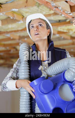 Frau in Baumeister Hardhut Befestigung der Decke Stockfoto