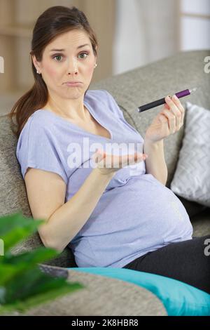 Charmantes Mädchen mit Baby im Bauch hält eine elektronische Zigarette Stockfoto