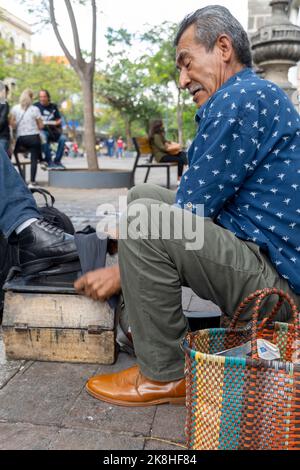 Älterer Latino-Mann, dunkelhäutig, putzende und glänzende Schuhe, glücklich mit seinem Beruf mexiko Stockfoto
